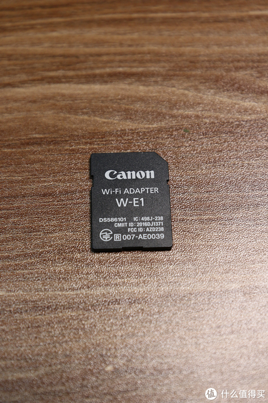 真身来了！靠！这不就是一张SD卡吗？您还真说对了一点，这个Wi-Fi适配器W-E1就是一个SD卡造型的配件。把它放置到7D2/5DS/5DSR的双卡槽中，就可以传输另外一个卡槽里CF卡上的照片，同时还能遥控操作相机。当然，这个适配器本身是没有存储功能的。
