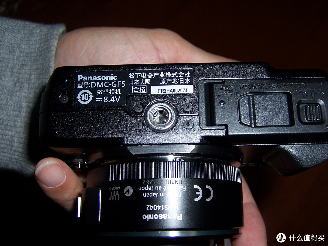 相机底部，机身和镜头应该都是日本制造。另外还有电池仓和存储卡槽。