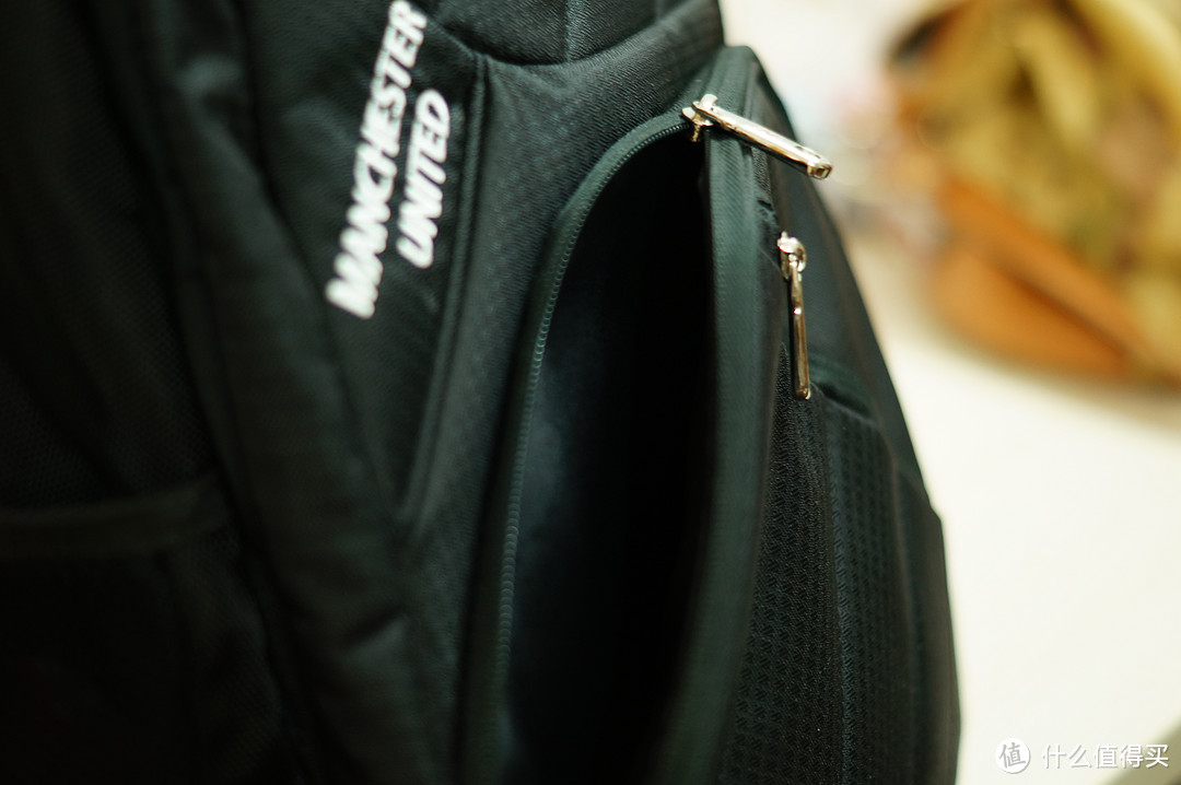 前面这个口袋的一边设计成倾斜式，把包从背后翻到前面开拉链的