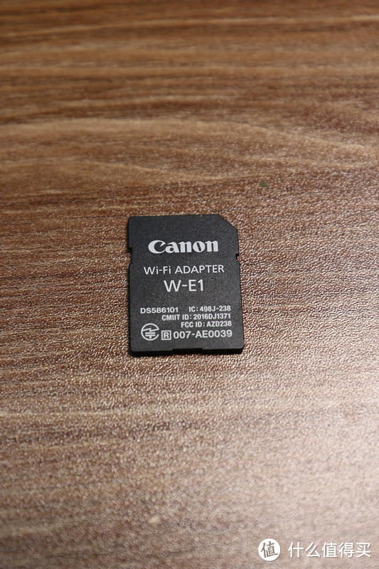 真身来了！靠！这不就是一张SD卡吗？您还真说对了一点，这个Wi-Fi适配器W-E1就是一个SD卡造型的配件。把它放置到7D2/5DS/5DSR的双卡槽中，就可以传输另外一个卡槽里CF卡上的照片，同时还能遥控操作相机。当然，这个适配器本身是没有存储功能的。