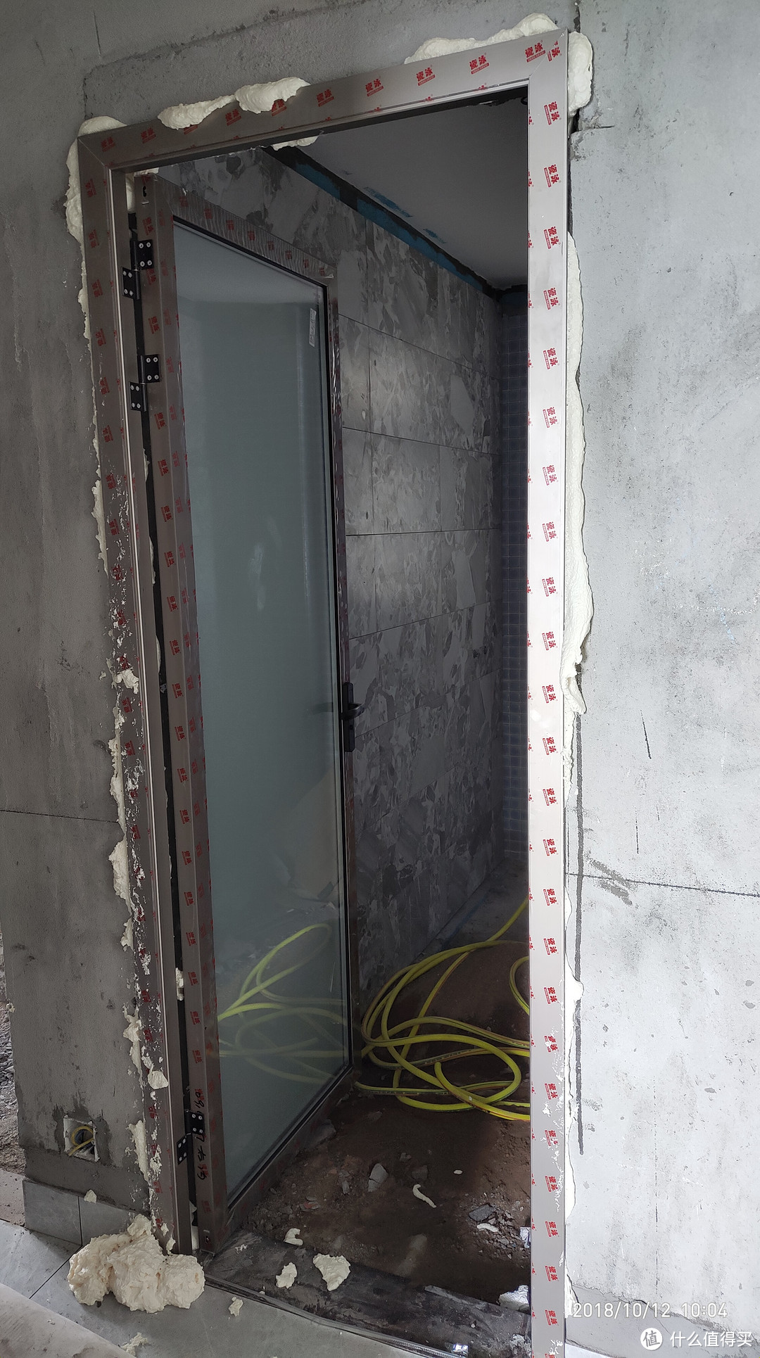 客卫铝合金玻璃门，旁边的是泡沫胶，保护膜还有一层，泥水师傅自己安装，省了每个门80元的安装费用，窄框门，厂家忘了去掉玻璃上的水印LOGO，唉。。。