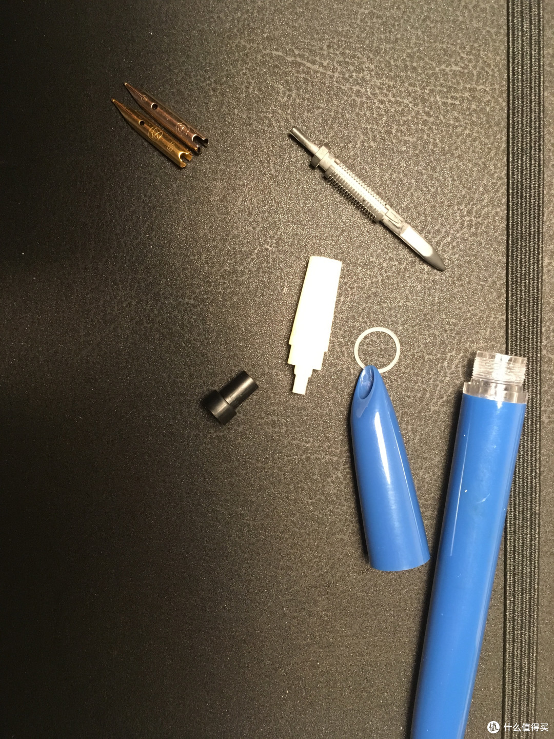 可以看到零件做工也是很不错的，白色的圆圈是垫在笔握里面防止漏墨的，目前拆卸的暗尖钢笔只有这款有这种设计，就算重新装回去不上硅油也不不会漏墨，上面那根是华孚118的金尖