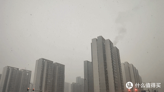 在某小区高楼处早晨因为太阳和阴云的影响所以能见度较低，楼也有供暖蒸汽和雪花有种应和的感觉