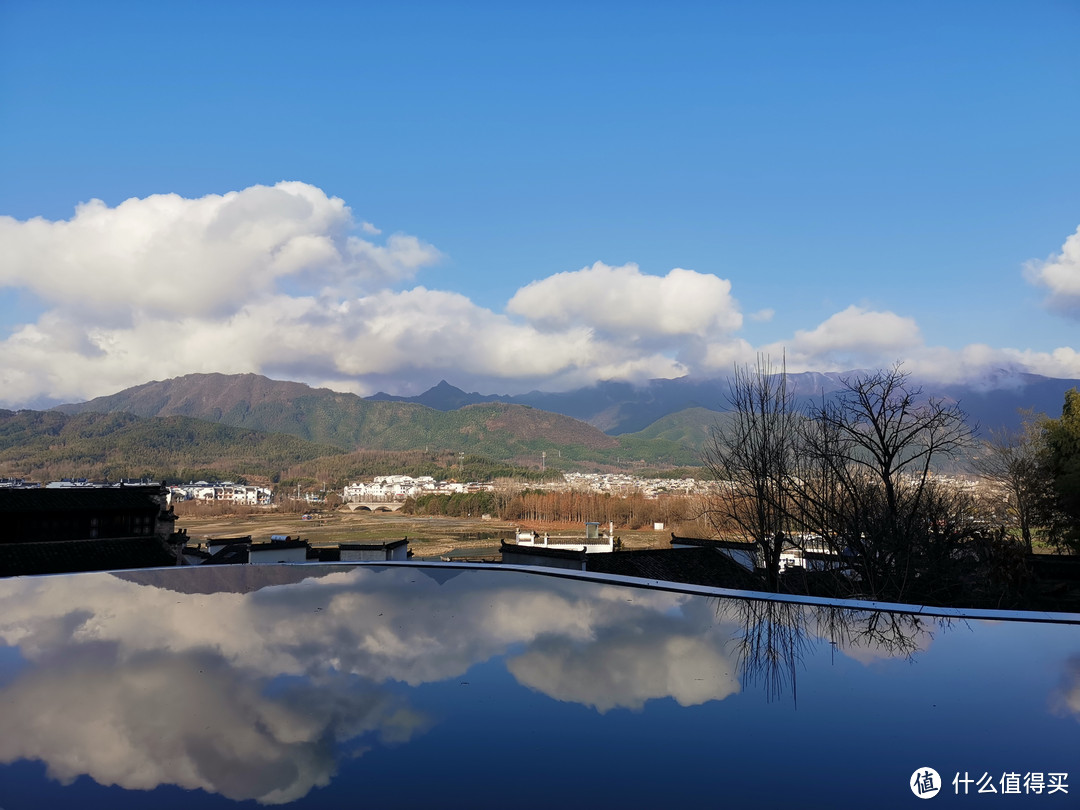 酒店的无边泳池，倒影着放晴的天空，远处即是宏村