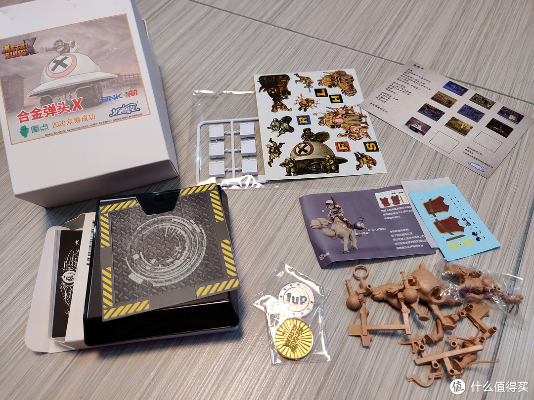 贴纸一套，一张感谢卡，2个金属游戏币，一个支架，动物载具骆驼以及Fio人物模型，补给箱（白色的那个小白方块，需要自行贴贴纸）