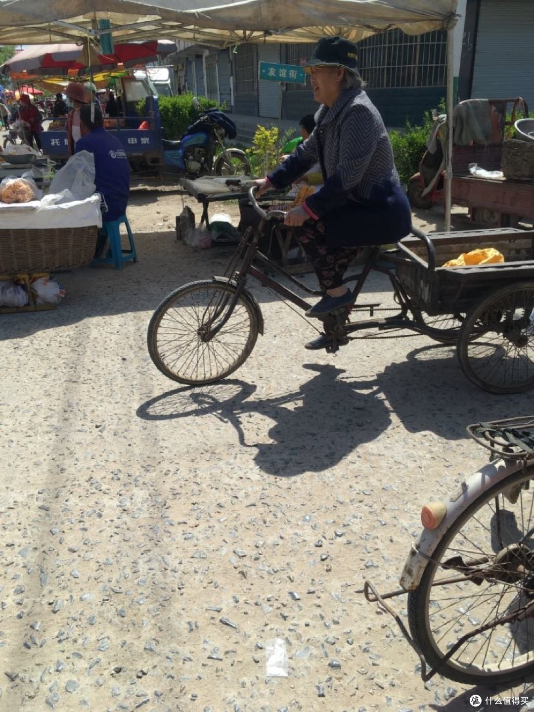 车来车往的集市。一辆二轮自行车向南行驶，一辆三轮自行车向北行驶。