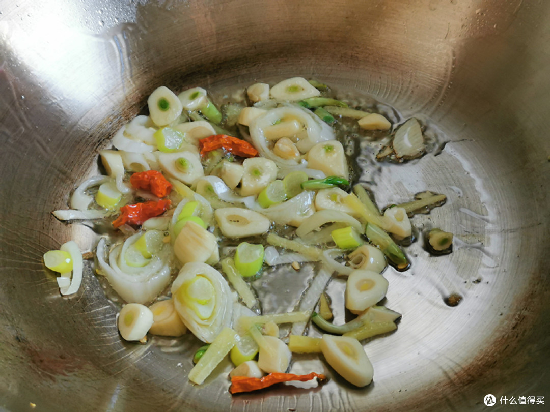 锅中倒入花生油,把葱花、姜丝、蒜片和干红辣椒倒入炒出香味;