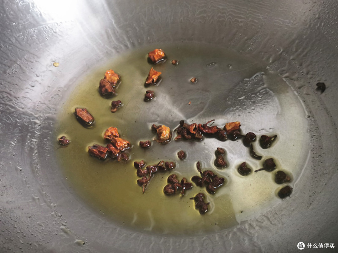 锅中倒入花生油，把干红辣椒段和花椒一起倒入炒出香味关火；