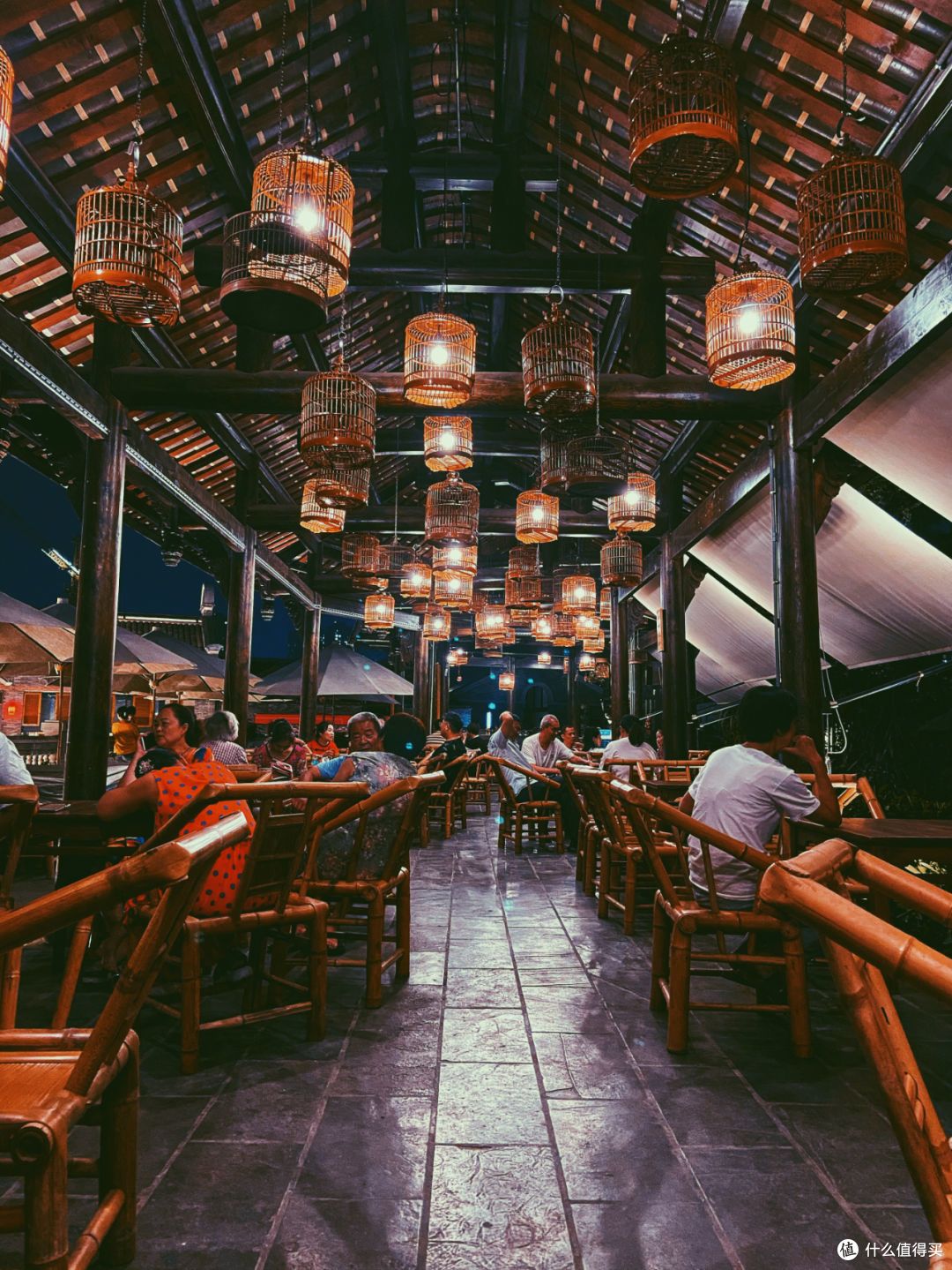 人们坐在茶馆的竹椅上享受夏夜休闲时光。©️图虫创意
