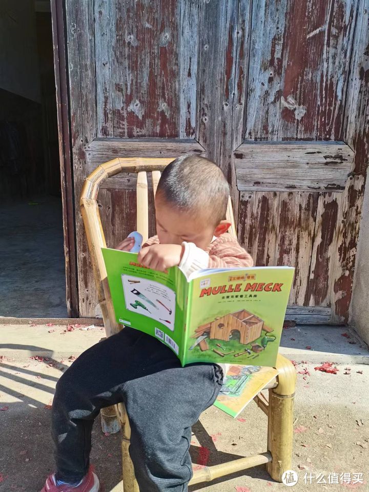 弟弟坐在乡下爷爷奶奶家门口点读书本