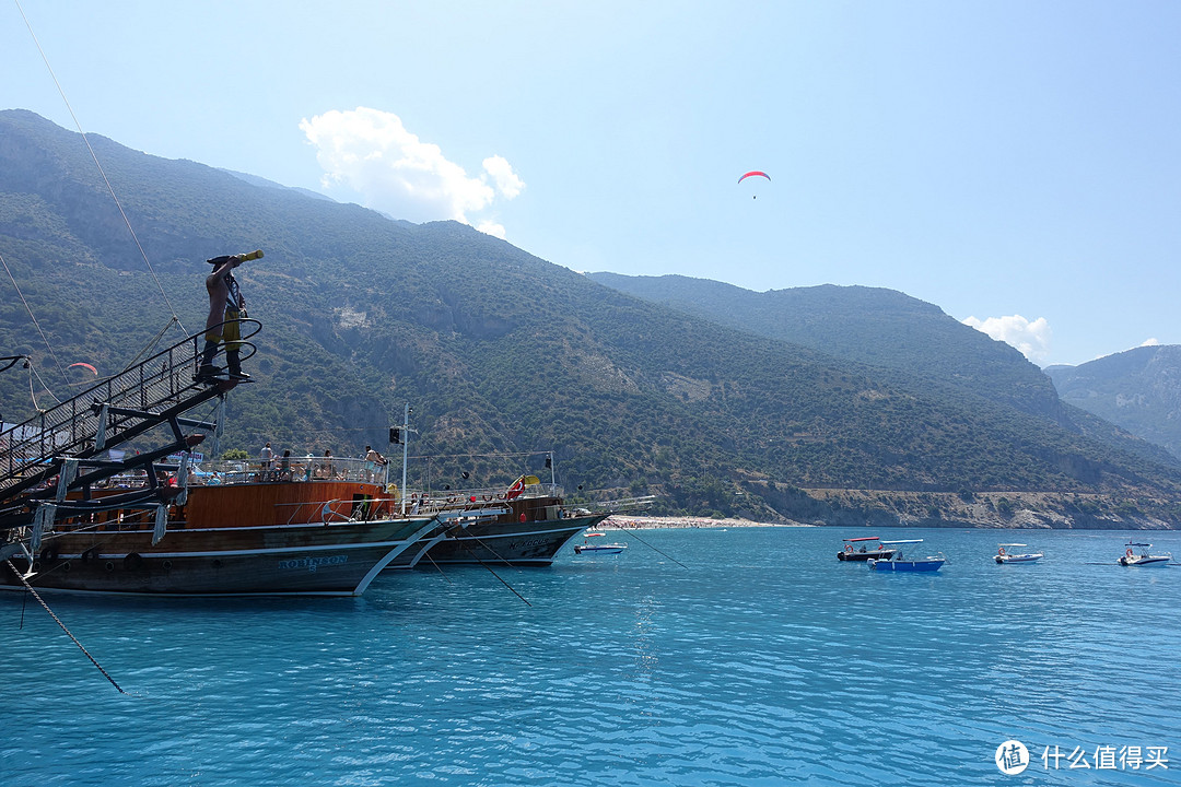 游船会在近海开一段，背后山上有人在玩滑翔伞。