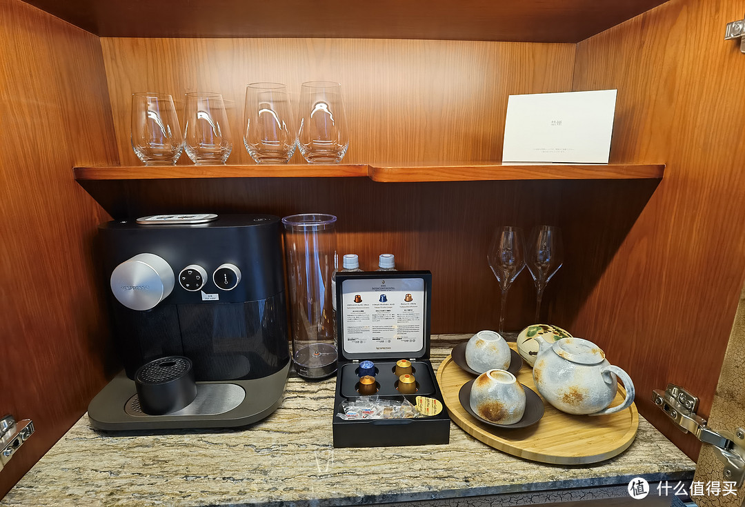 吧台的上面是杯子、茶具、饮用水、胶囊咖啡机和胶囊