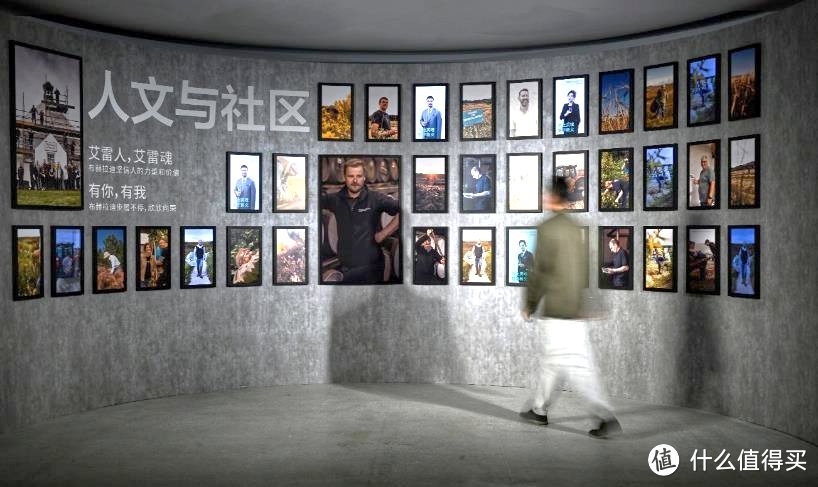 A person walking past a wall of pictures  Description automatically generated