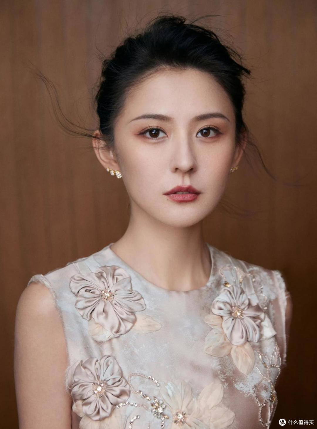 热依扎一身无袖浅色旗袍裙,姿态如古典仕女,格外明媚动人
