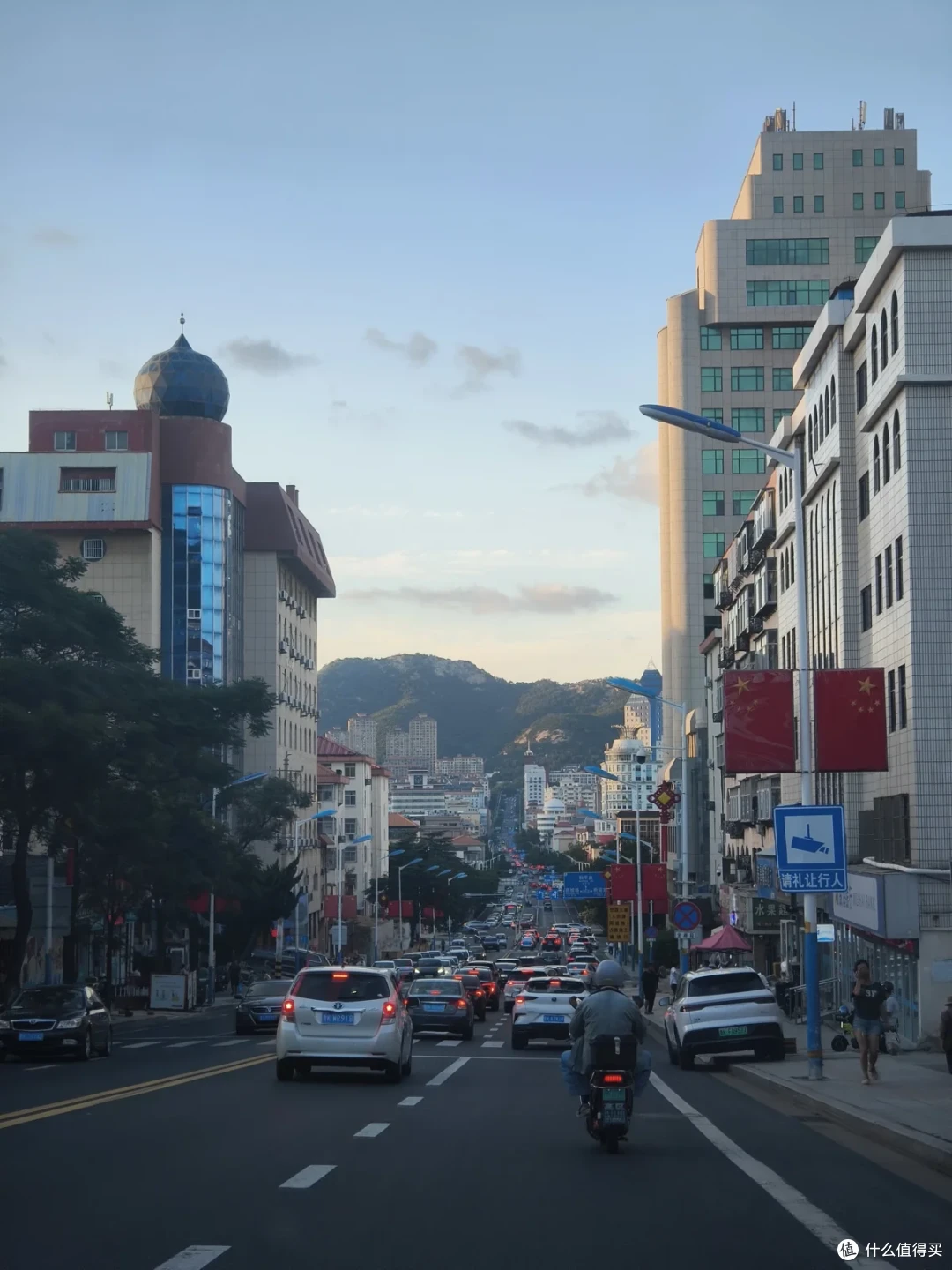 威海市区的主干道纵深向前，车流密集，道路尽头立着苍翠山峦