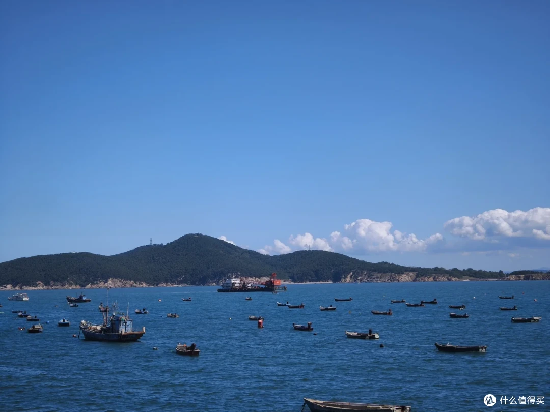 海源公园前的海湾泊满小渔船，对岸刘公岛青山连绵