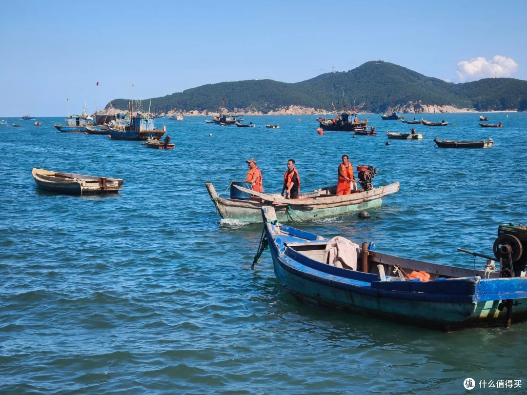 海源公园外的海面上，三名穿橙色救生衣的渔民驾着木舢板，四周泊满渔船