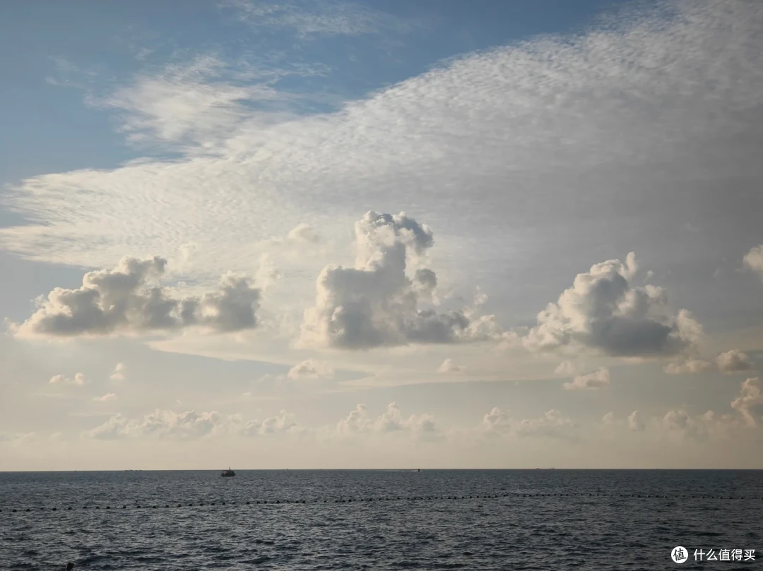 国际海水浴场上空云层堆叠，阳光穿透云隙洒向平静海面