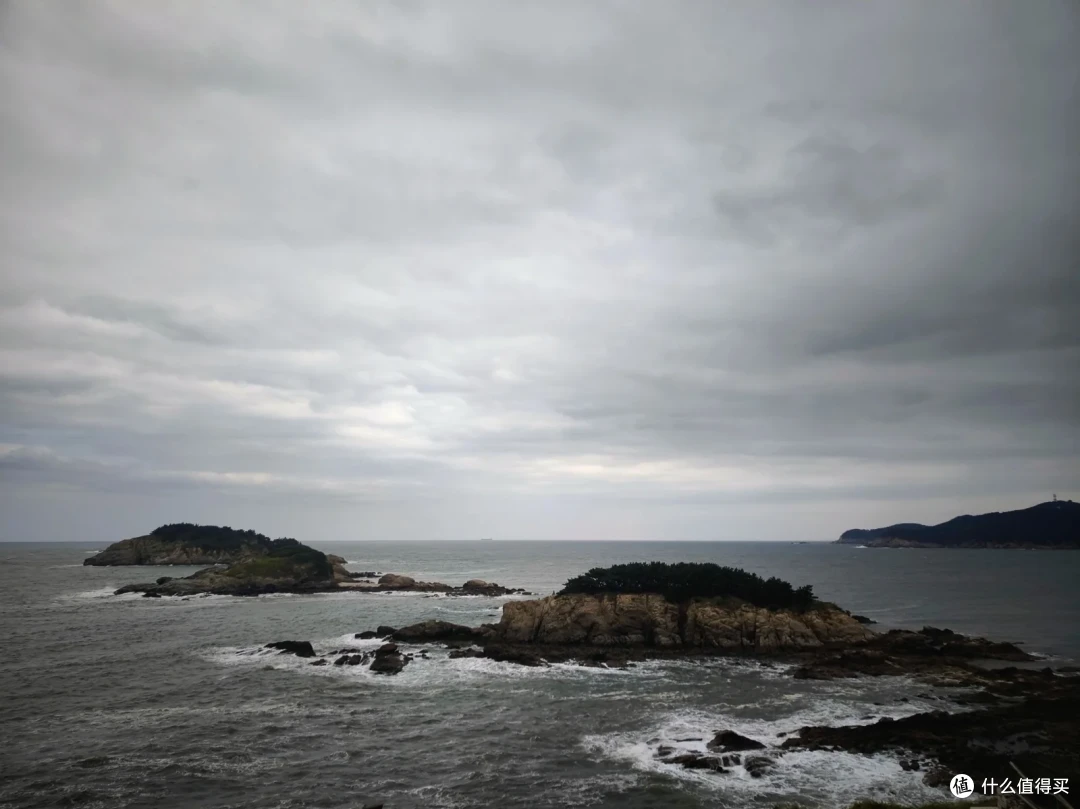 阴云下的三连岛海景，礁石小岛上长着松树，海浪拍打岸边
