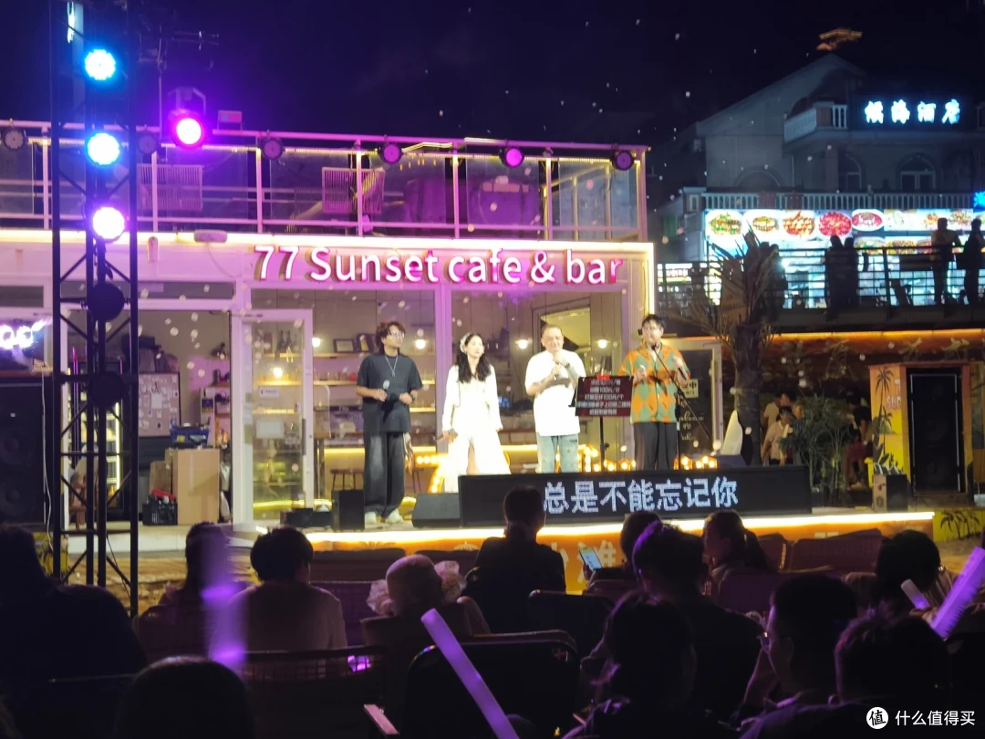 入夜后海滩边的77 Sunset cafe&bar舞台上歌手演唱，台下坐满观众