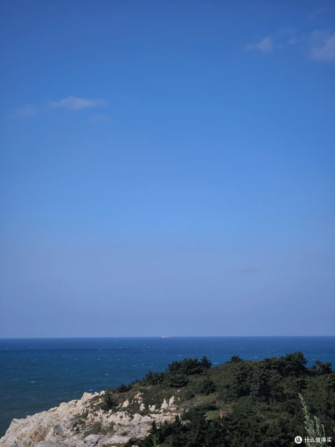 从猫头山观景台俯瞰，礁石峭壁下一片深蓝色大海，远处有船