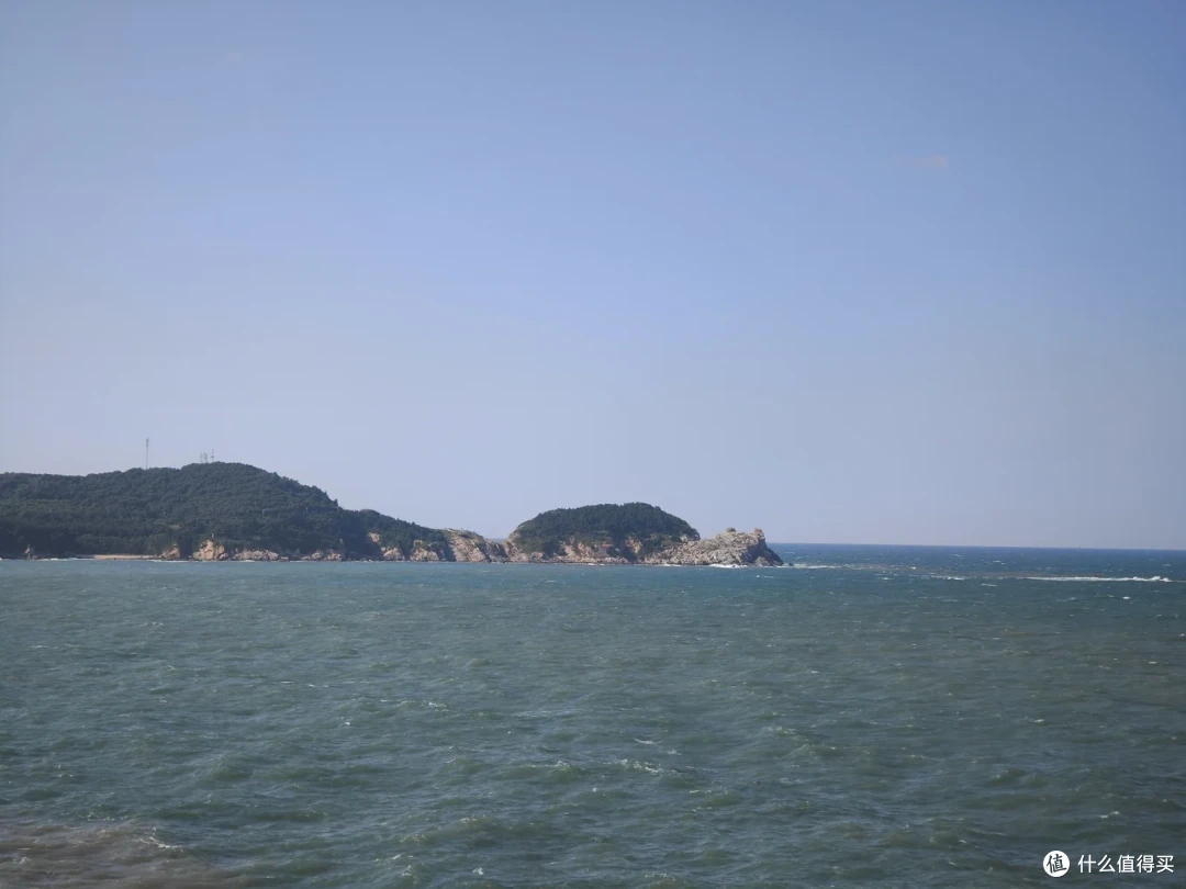 远眺猫头山，植被覆盖的山体绵延探入海中，轮廓像只趴在海上的猫