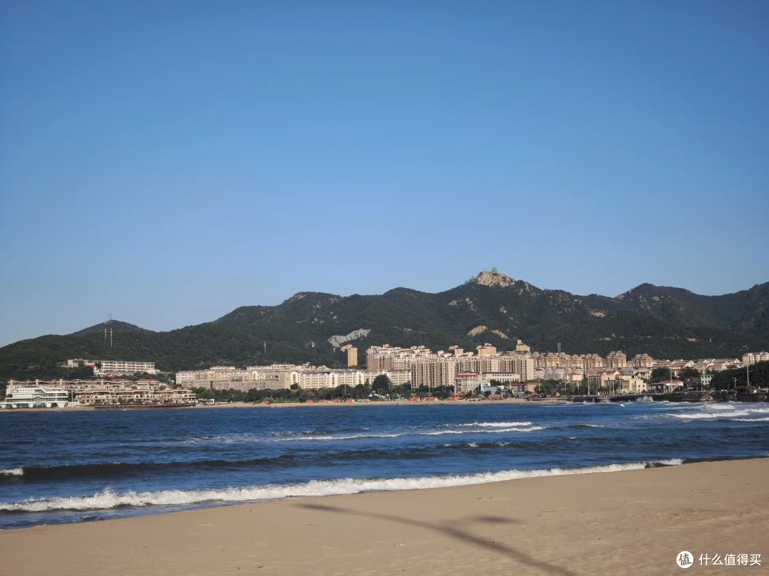 金海滩的浪一排排涌上岸，对面狭长半岛的山脚下立着密集楼群