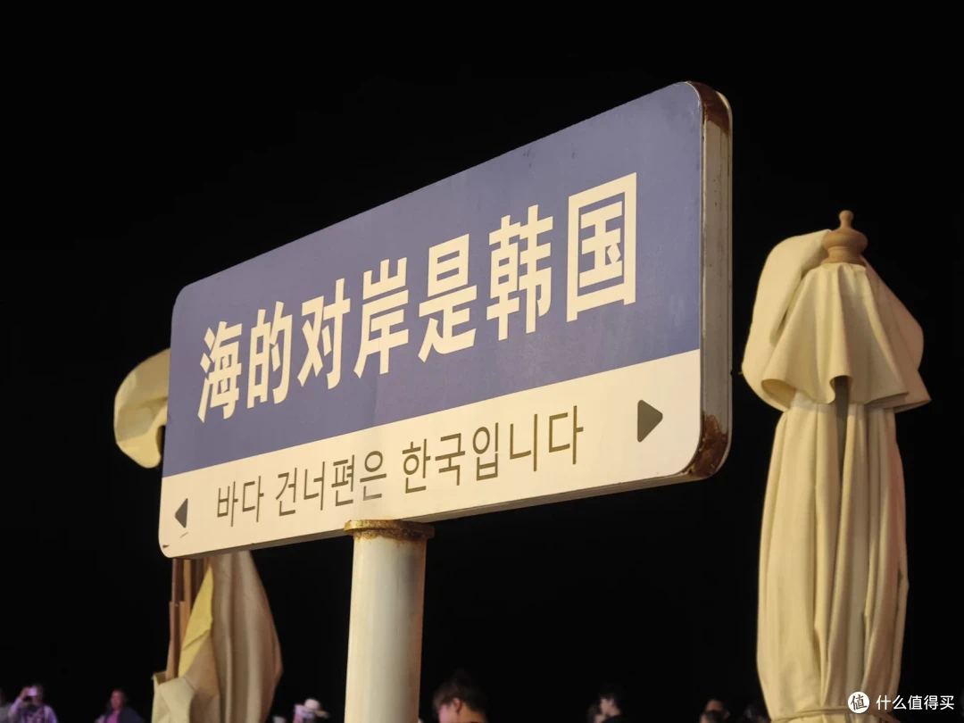 夜晚沙滩边立着中韩双语标牌：海的对岸是韩国