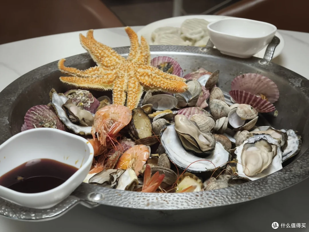 海鲜大咖端上桌，海星、生蚝、扇贝、大虾铺满铁盘，花蛤打底