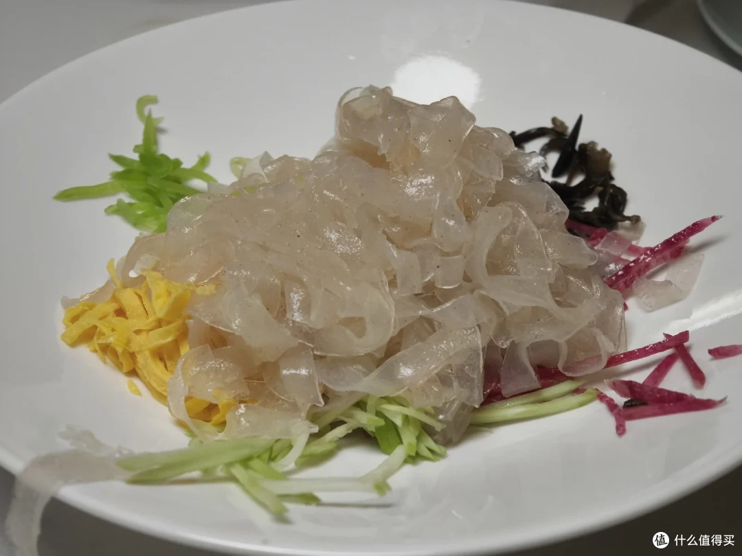 拌辣酱吃的米皮，晶莹的米皮堆在白盘中央，四周围着蛋丝、黄瓜丝、紫萝卜丝和木耳