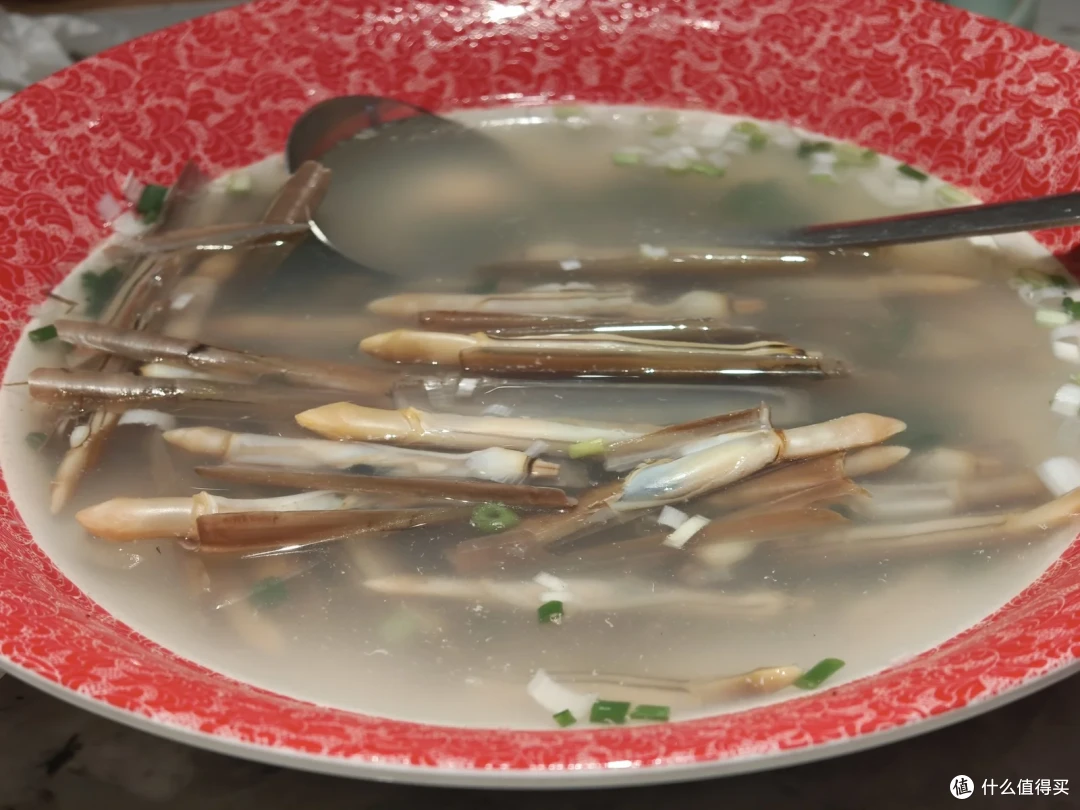 红边大碗里的清汤细长贝类，汤色清亮撒着葱花