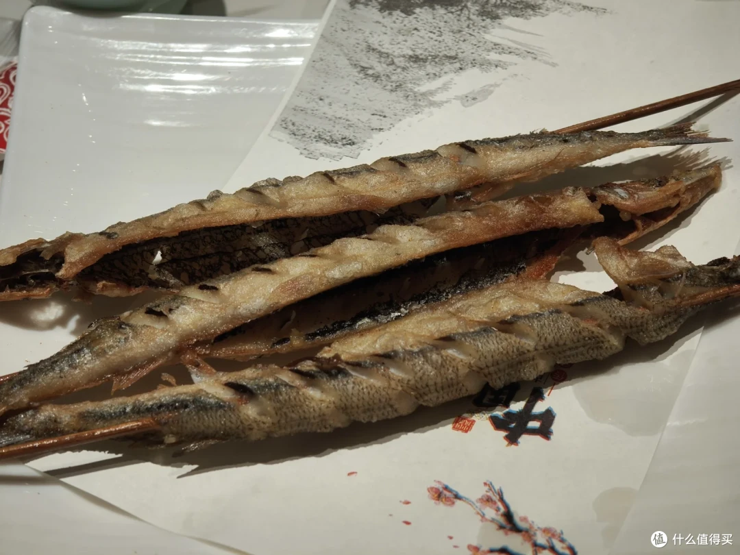 油炸针鱼，金黄酥脆的细长鱼身叠放在白瓷盘中