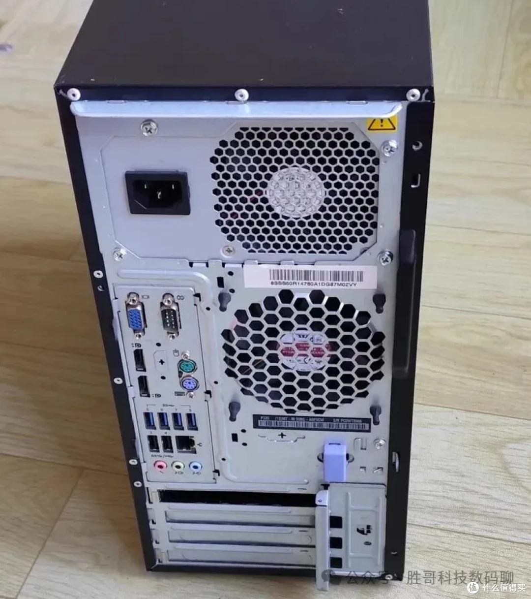 联想 ThinkStation P320 塔式后面板实拍（VGA、串口、USB 2.0 与 USB 3.0 接口，右侧为机箱风扇蜂窝网罩与整机条码铭牌，下方四片 PCIe 挡板）
