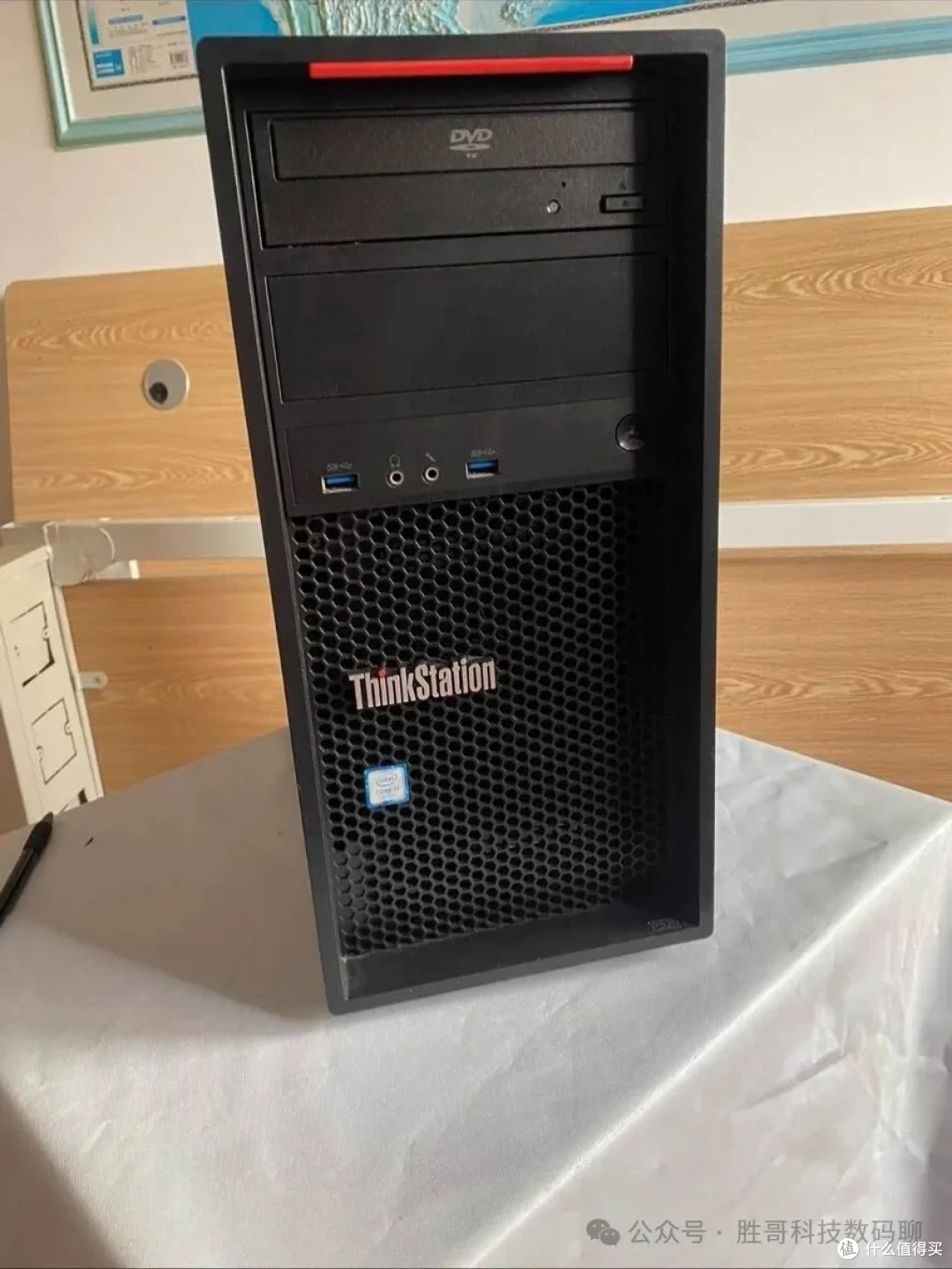 联想 ThinkStation P320 塔式整机正面实拍（顶部红色提手、DVD 光驱位与一个空的 5.25 寸位、前面板两组 USB 3.0 与音频接口，下方蜂窝进风网孔上印 ThinkStation 标识）