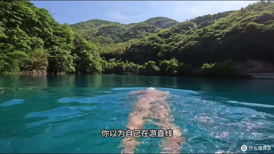 开放水域中的游泳者及周围山林景观