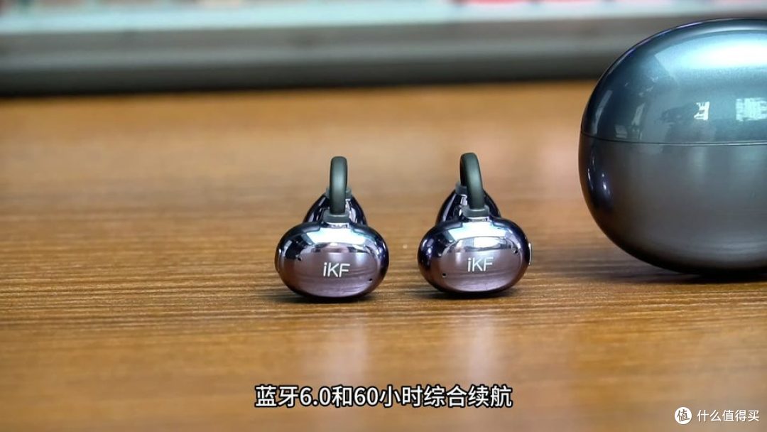 两只耳机放在木质桌面上，右侧是充电盒。