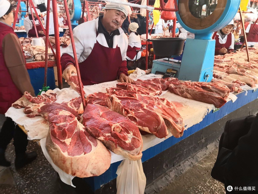 农贸市场牛肉摊位实拍，鲜牛肉整齐陈列，摊主现场打理售卖