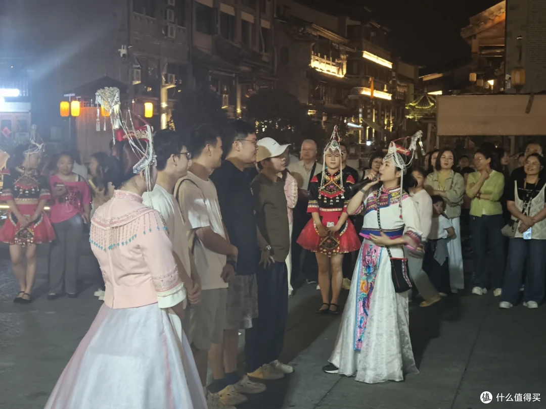 夜色中的畲乡风情街，穿民族服饰的演员被举手机的游客围住