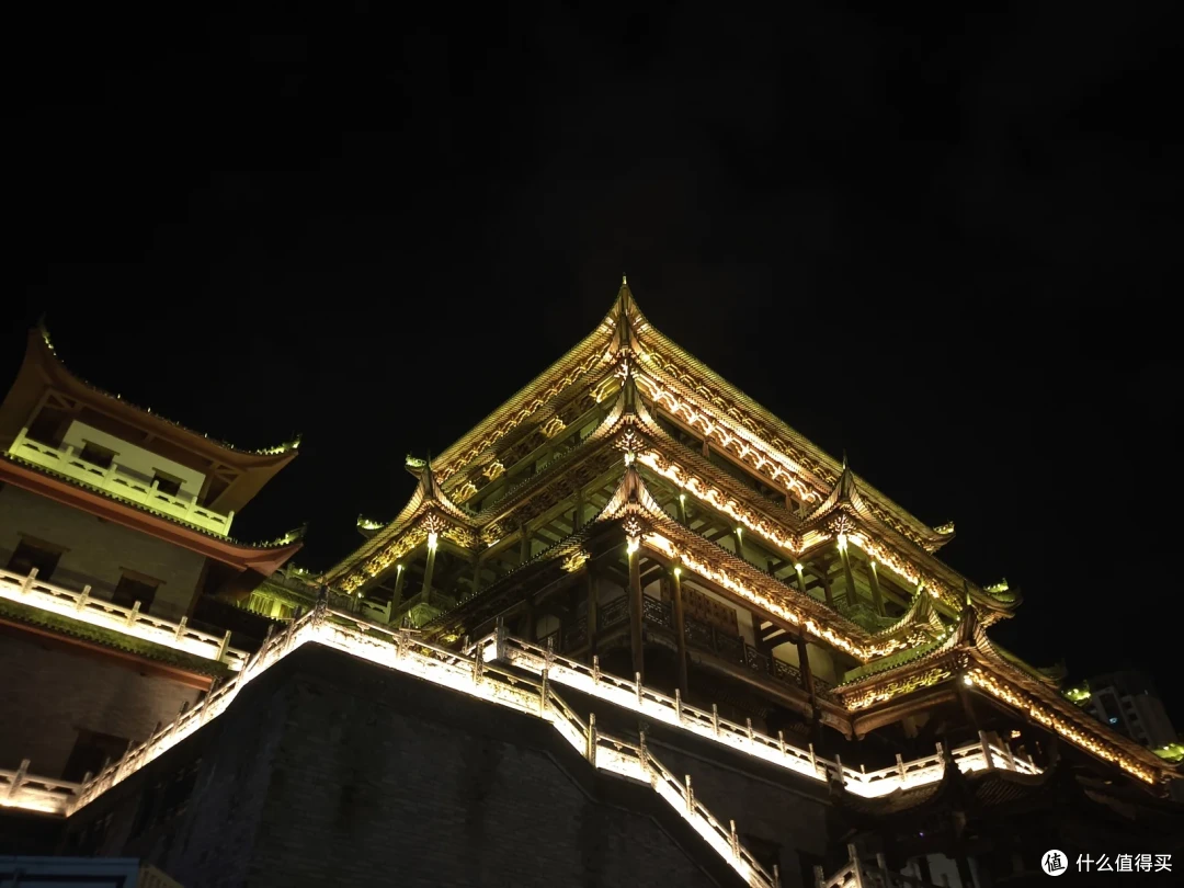 夜色中被灯光照亮的仿古楼阁，层层飞檐沿石砌台基向上收拢