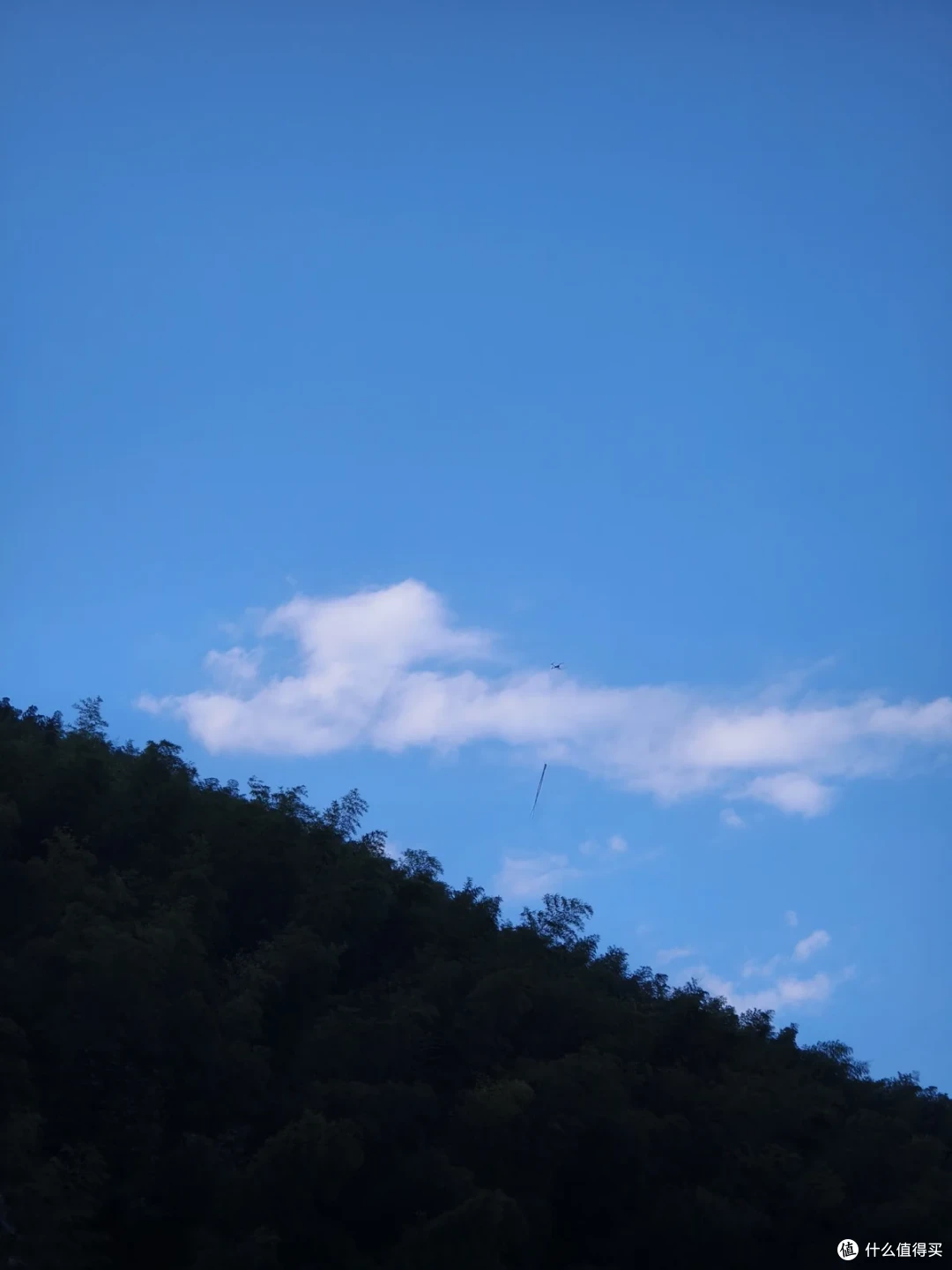 山坡上投着一大片云影，上半部是蓝天