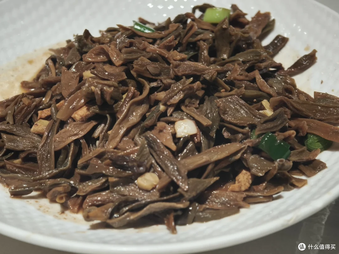 一盘深褐色的干豆角炒菜，泛着油光