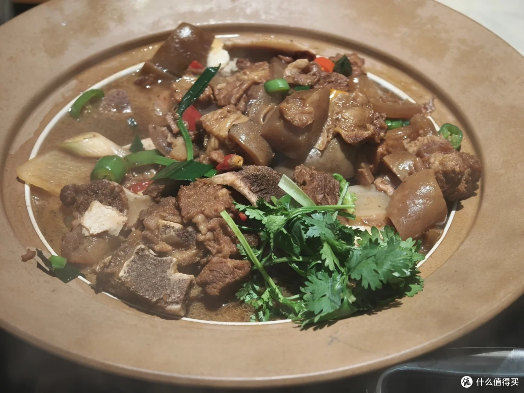 陶盘里是带皮牛肉块，汤汁浓稠，上面撒着香菜