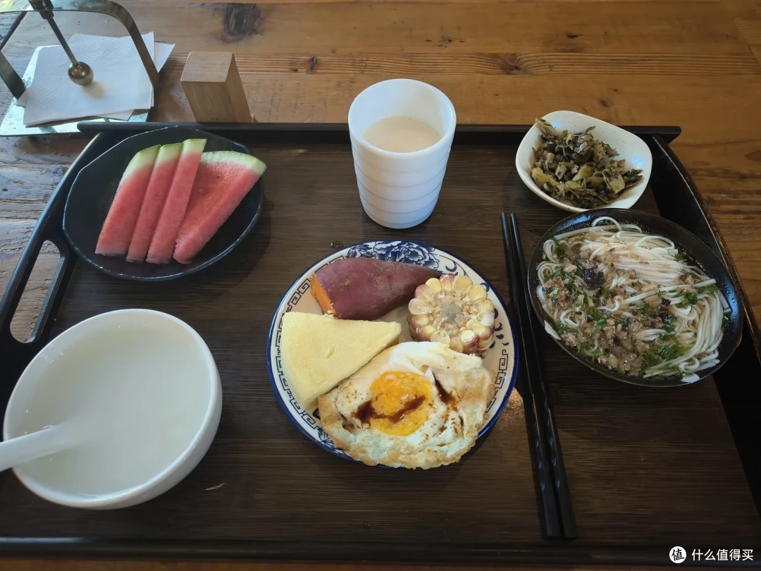 木托盘上的早餐，有米粉、煎蛋、西瓜、小菜和一碗豆浆