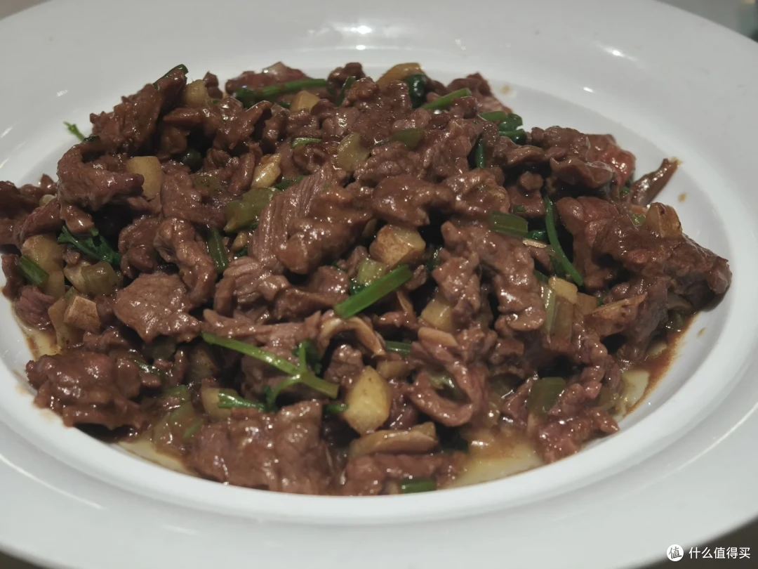 白瓷盘里是炒牛肉粒，配着青蒜和芥菜干