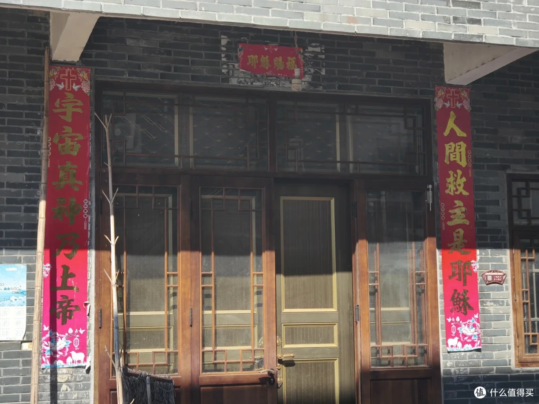 砖墙木门两侧贴着红色基督教对联，门上是红底横批