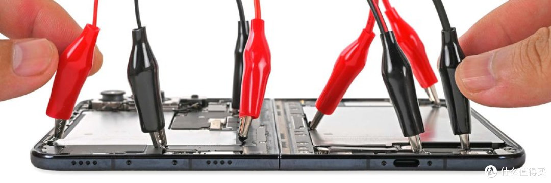 半开状态下，探针夹在铰链与机身连接处做通电检查。图源：iFixit 官方拆解